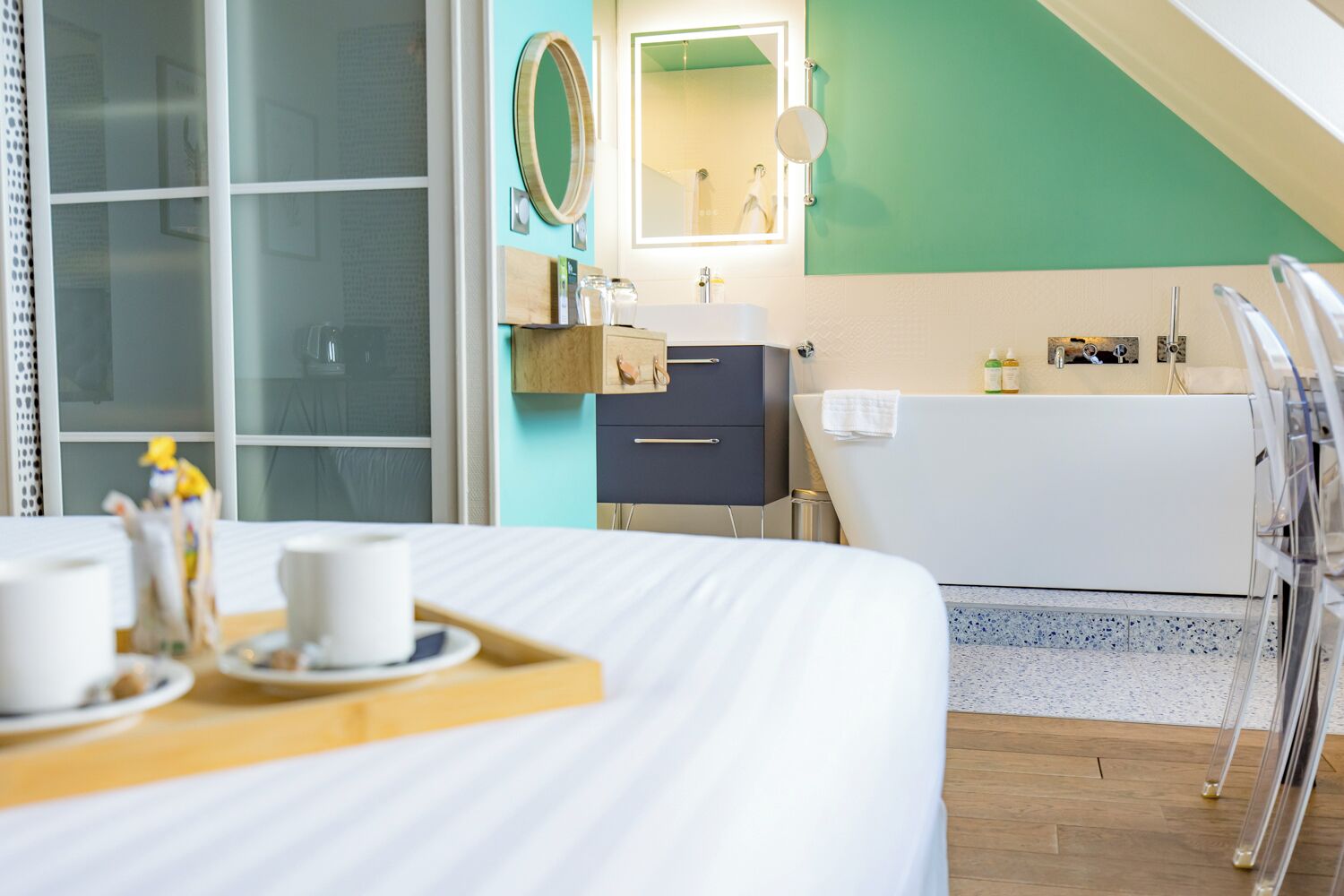 A hotel room with a bed, a bathroom with a bathtub, a sink, and a mirror.