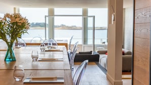A dining area with a wooden table, chairs, and a vase of flowers. - Hôtel la Baie des Anges, son SPA marin et sa piscine couverte et chauffée (Landéda)
