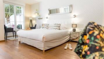 A bedroom with a large bed, bedside tables, a mirror, and a chair.