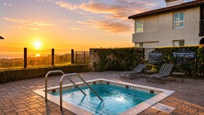 A swimming pool with a view of the sunset, lounge chairs, and a building with a sign indicating no lifeguard on duty. - Pool + Hot Tub Access + Gym | Gated, Newport Beach | Seabreeze Retreat (Dana Point)