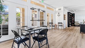 A spacious room with a large dining table, chairs, and a bookshelf. - Pool + Hot Tub Access + Gym | Gated, Newport Beach | Seabreeze Retreat (Dana Point)
