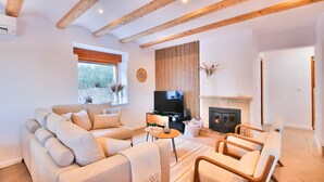 A living room with a sofa, chairs, a TV, a fireplace, and a window with a view of trees. - Modern villa with swimming pool and sea views in Denia (Denia)