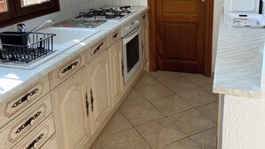 Une cuisine équipée d’une cuisinière, d’un four et de meubles de rangement en bois.
