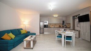 Un salon moderne avec un canapé de couleur turquoise, une table basse et un coin repas avec des chaises blanches.