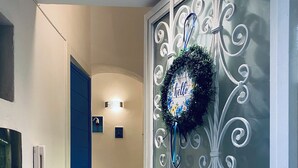 Een deur met ingewikkeld metaalwerk, een blauw deurkozijn en een krans met de tekst 'hello'.