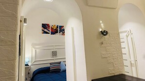 Een slaapkamer met een bed, nachtkastje en een lamp aan de muur.