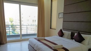 Ένα δωμάτιο ξενοδοχείου με ένα μεγάλο κρεβάτι, θέα στην πόλη από ένα μπαλκόνι και μοντέρνο σχεδιασμό.