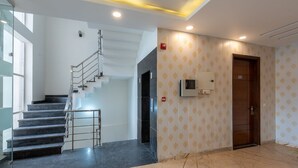 Ένας μοντέρνος εσωτερικός χώρος με μια μαρμάρινη σκάλα, ένα σύστημα πυρανίχνευσης και έναν τοίχο με διακοσμητικό σχέδιο.