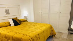 Una habitación con una cama, un armario y una mesita de noche.