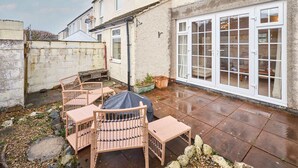 A patio with wicker furniture, a covered table, and a large sliding glass door. - Host Stay Trinity Way (Keswick)