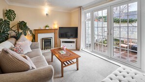 A living room with a sofa, a coffee table, a TV, and a fireplace. - Host Stay Trinity Way (Keswick)