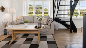 A modern living room with a sofa, coffee table, and a staircase. - "Mari" - 150m from the sea by Interhome (Tranekær)