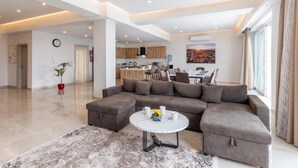 A spacious living area with a sectional sofa, a dining table, and a kitchen in the background. - Magnifica Gozitan Villa Pool And Jacuzzi (Xaghra)