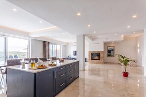 A modern kitchen with a large island, dining area, and a view of the outdoors. - Magnifica Gozitan Villa Pool And Jacuzzi (Xaghra)