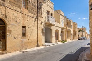 Una strada con edifici caratterizzati da portali ad arco e balconi.