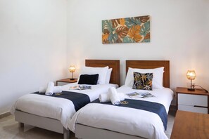 A hotel room with two beds, each with a wooden headboard, white bedding, and a small bedside table with a lamp. - Magnifica Gozitan Villa Pool And Jacuzzi (Xaghra)