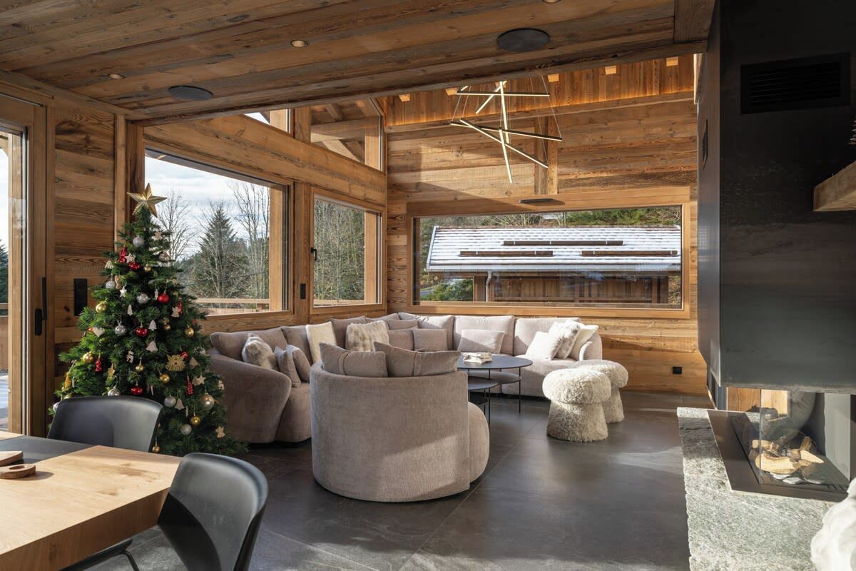 Een modern interieur met een houten plafond, een groot raam, een open haard en een kerstboom.