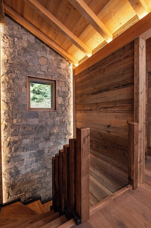 A wooden staircase with a stone wall and a framed picture.