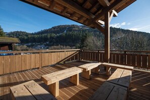 Una terrazza in legno con tavoli da picnic che si affaccia su un paesaggio montuoso.