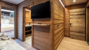Une chambre moderne avec un intérieur en bois, un téléviseur à écran plat fixé au mur et une porte coulissante donnant sur un espace extérieur.