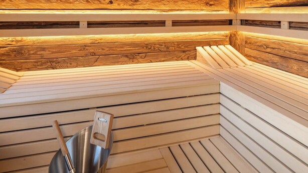 Un sauna en bois avec des bancs et un seau en métal.