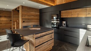 Une cuisine moderne avec un lambris en bois, un îlot central doté de tiroirs et une cuisinière encastrée.