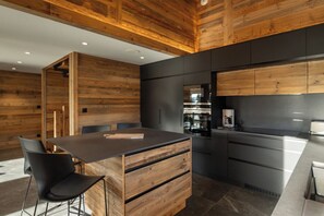Una cucina moderna con rivestimenti in legno, un'isola centrale con cassetti e un piano cottura integrato.