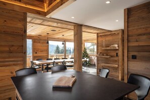 Un interno moderno con un ampio tavolo da pranzo in legno, sedie nere e vista sull'esterno.