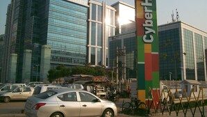 A modern building with a sign reading "CyberHub" and several parked cars in front.