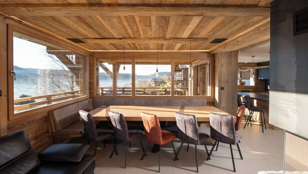 A modern interior with a wooden ceiling, a long dining table, and seating.