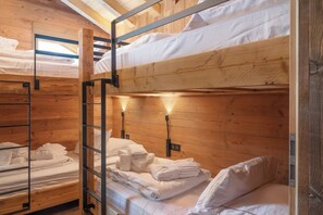 Habitación con literas, paredes de madera y barandillas de metal.