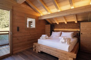 A wooden cabin bedroom with a bed, a window, and a door.