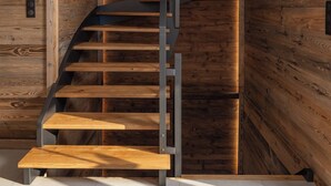 A spiral staircase with wooden steps and metal railings, built into a wall with wooden paneling.