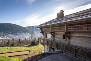 Una cabaña de madera con balcón con vistas a un valle y un pueblo lejano.