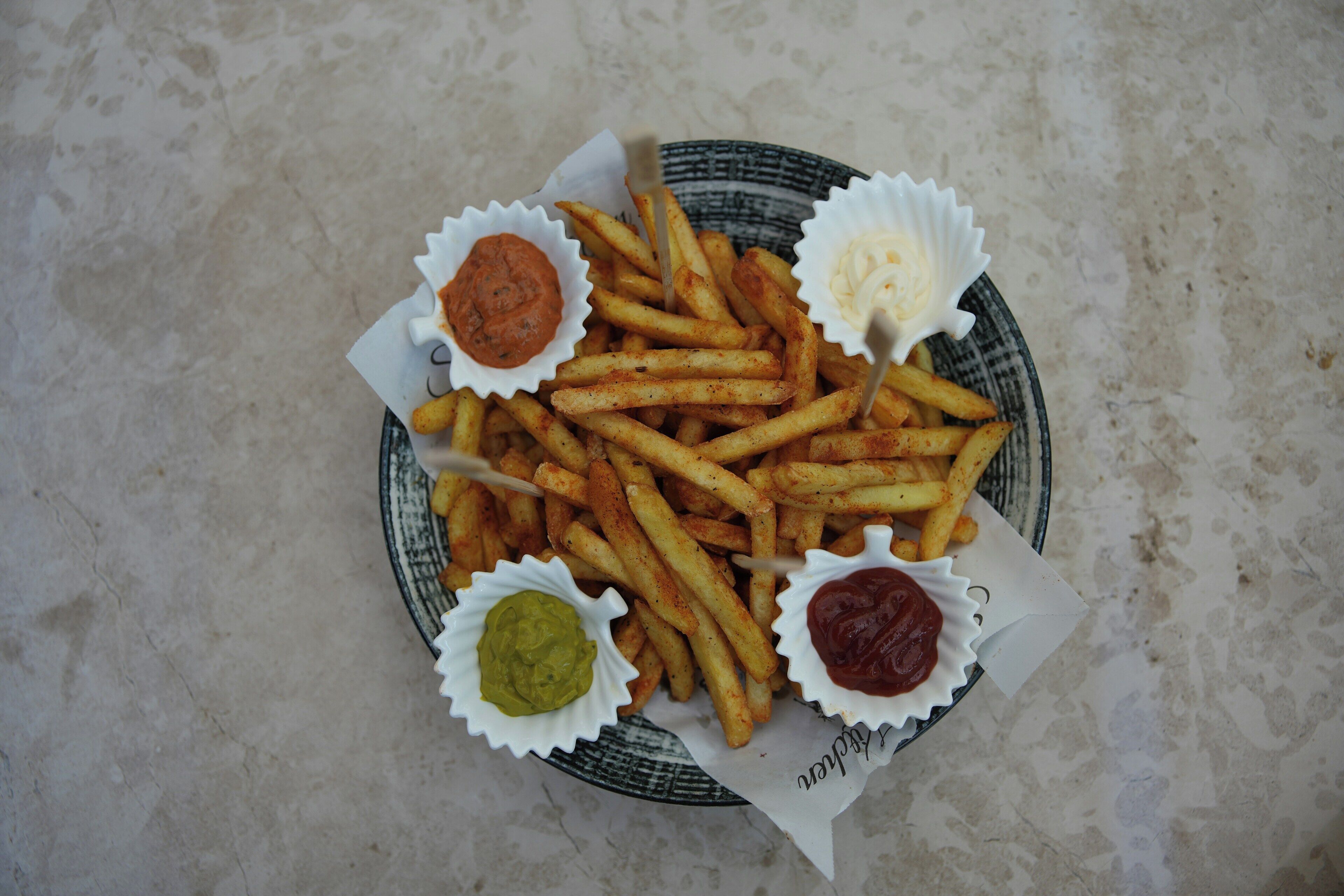 A plate of seasoned fries with four different dipping sauces.