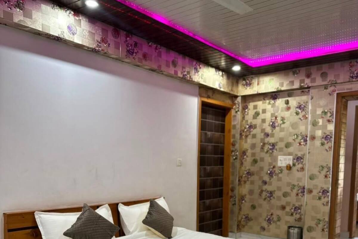 Ein Schlafzimmer mit Bett, Holz-Kopfteil, Deckenventilator und einem Badezimmer mit Dusche und Toilette.