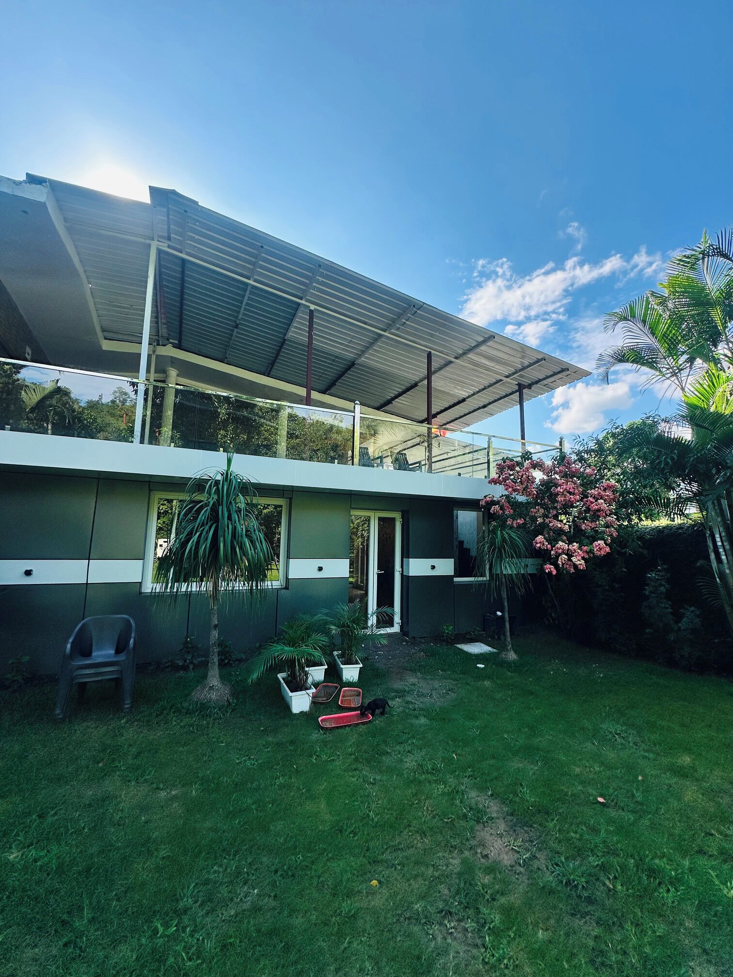 Una casa moderna con un porche cubierto, un jardín pequeño y cielo despejado.