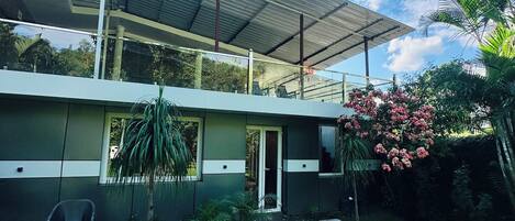 Una casa moderna con un porche cubierto, un jardín pequeño y cielo despejado.
