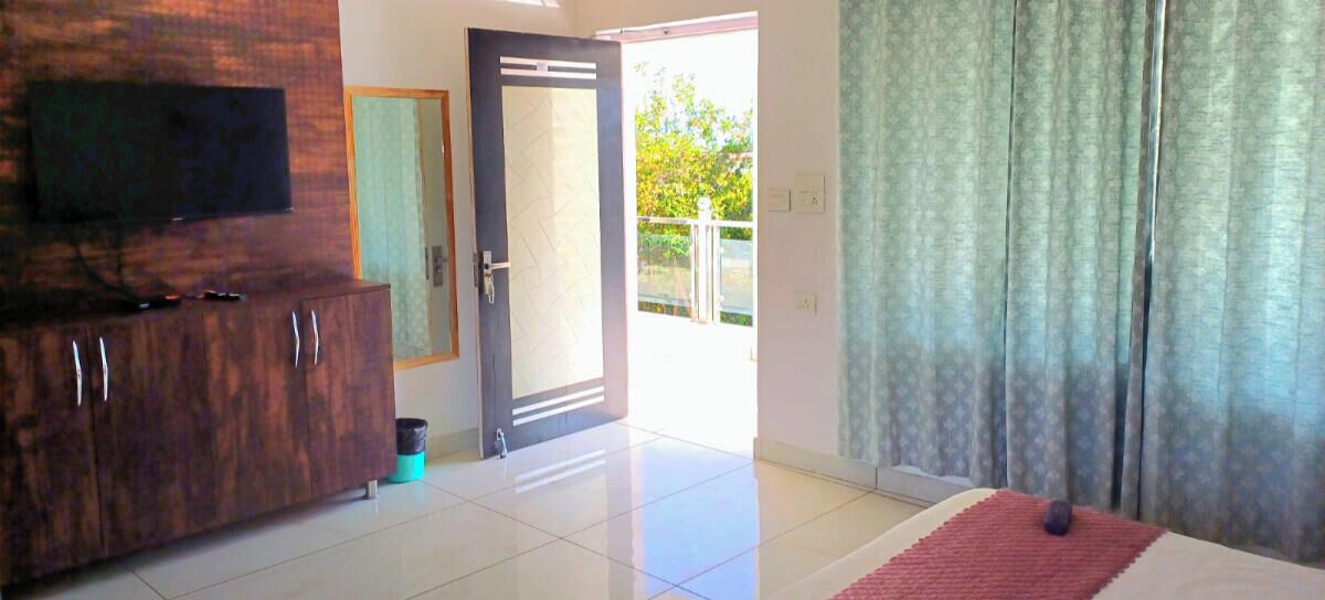 A spacious room with a large cabinet, a flat-screen TV, and a red rug.
