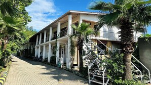 A multi-story building with a central courtyard, surrounded by palm trees and a paved walkway. - The Nature View Resort (Kaladhungi)