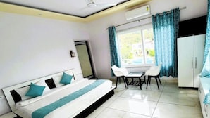 A room with a bed, a small table with chairs, a wardrobe, and a window with curtains. - The Nature View Resort (Kaladhungi)