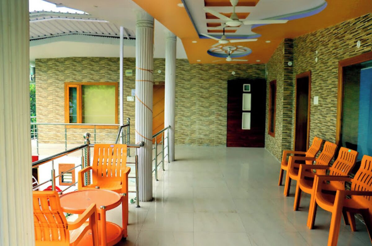 A spacious indoor area with orange chairs and tables, a staircase, and a stone wall.
