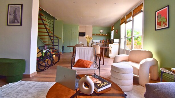 Amplia sala de estar con escalera, comedor y cocina.