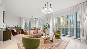 A spacious living room with a large window, a sofa, a coffee table, and a green armchair.