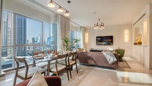 A modern living room with a dining area, large windows, a flat-screen TV, and a city view.