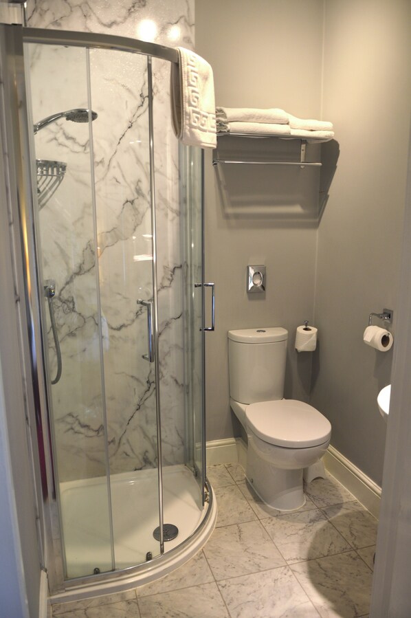Un baño con ducha de vidrio, inodoro y lavamanos.
