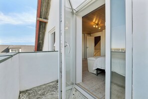 Ein Zimmer mit einem Bett, einem weißen Stuhl und einer Glastür, die zu einem Außenbereich führt.