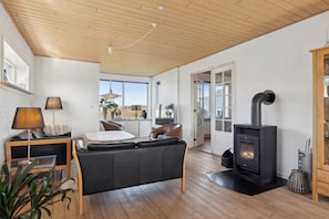 Una sala de estar moderna con sofá, mesa, lámpara, chimenea y vistas a través de una puerta abierta.
