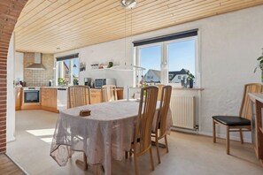 Una cocina amplia con electrodomésticos modernos, una zona de comedor con mesa y sillas, y ventanas grandes que ofrecen una vista.