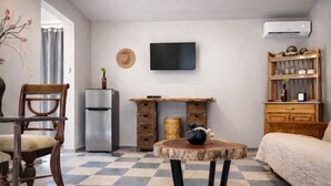 A compact living space with a dining table, a sofa, a TV, a refrigerator, and a bookshelf. - Bremar Collection Boutique Hotel (Celestún)